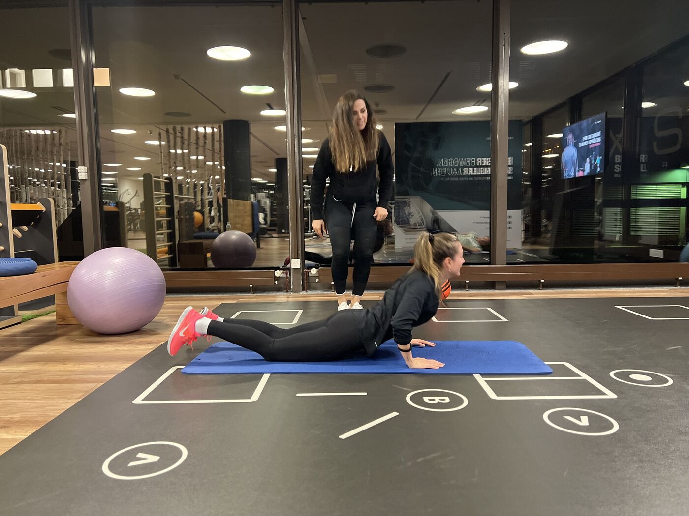 Coach betreut eine Kundin bei einer Übung auf der Trainingsfläche im AXIS Aesch